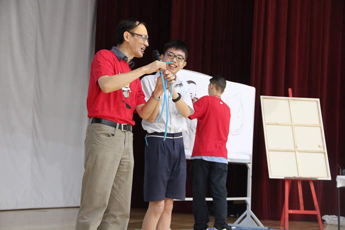 Teacher and student smiling on stage during an interactive school activity.